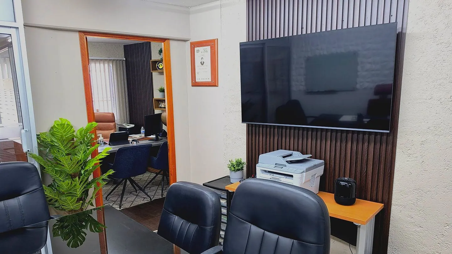 Área de trabajo de GMG Contadores con escritorios, impresora y pantalla
