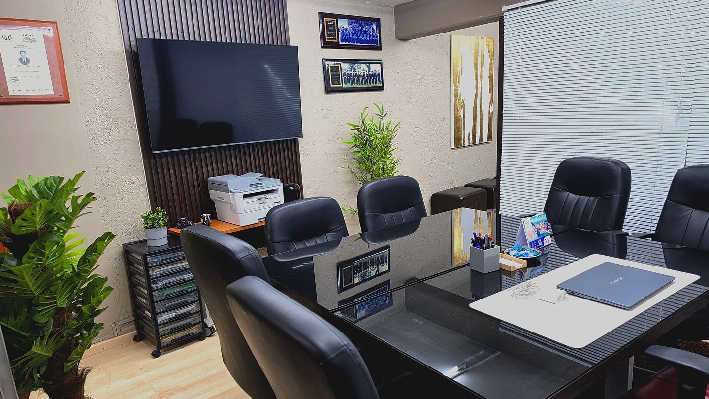 Sala de juntas de GMG Contadores: mesa de cristal para seis personas, pantalla de presentaciones y reconocimientos profesionales en el muro